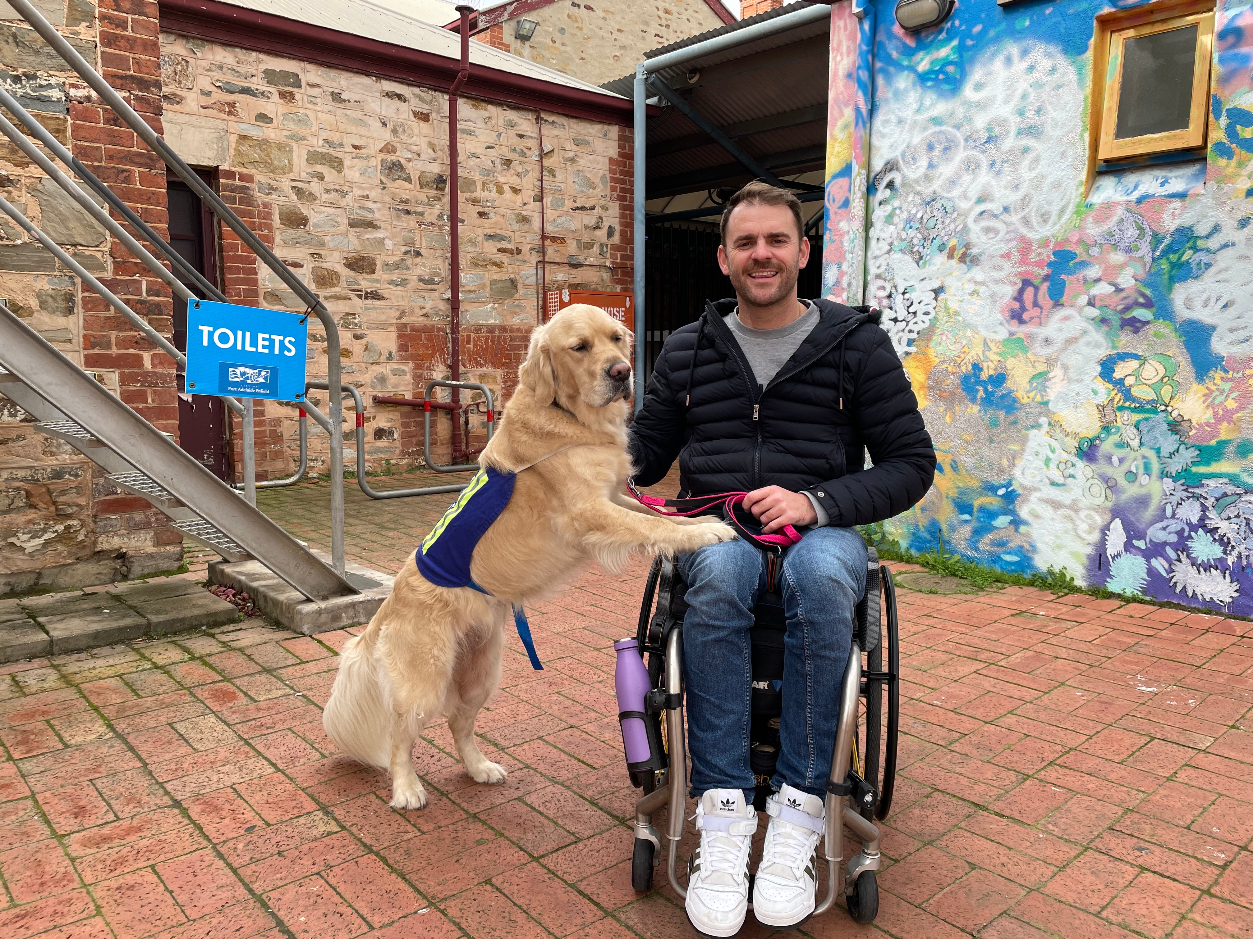 A man in a wheelchair with his service dog standing with its paws on his lap