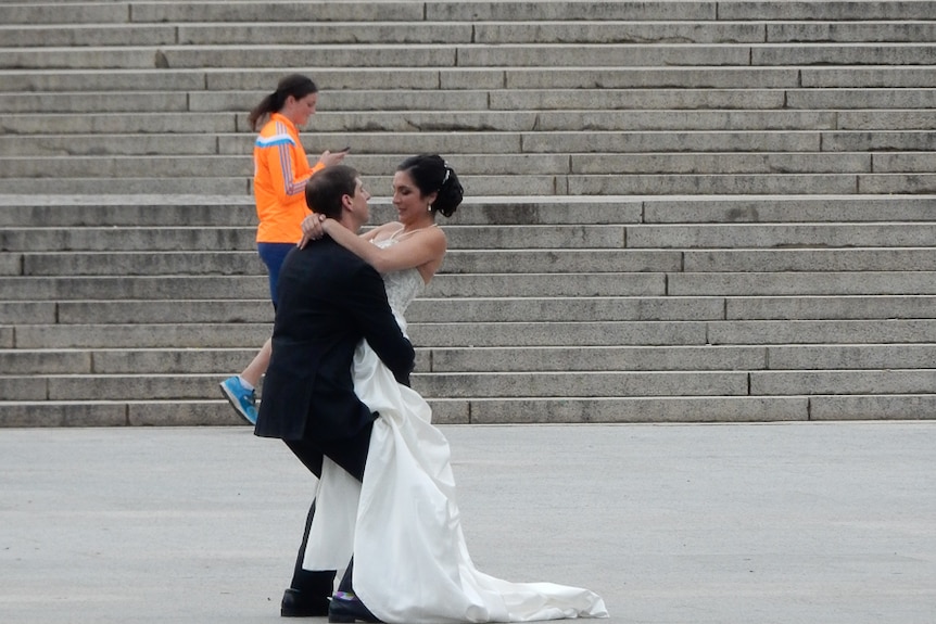 A bride and groom take photos near the Lincoln Memorial in Washington, DC
