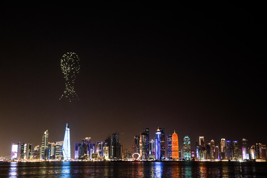 The shape of the World Cup trophy is illuminated over the Qatar skyline at night