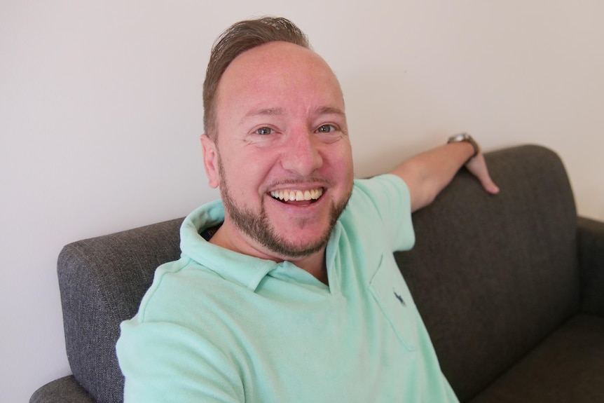 A man sitting on a couch smiling.