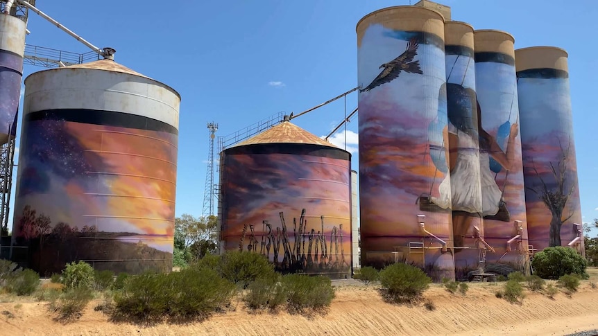 A line of silos with art painted on them.