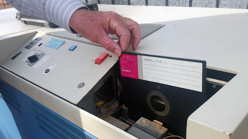 A floppy disk being inserted into an old computer.