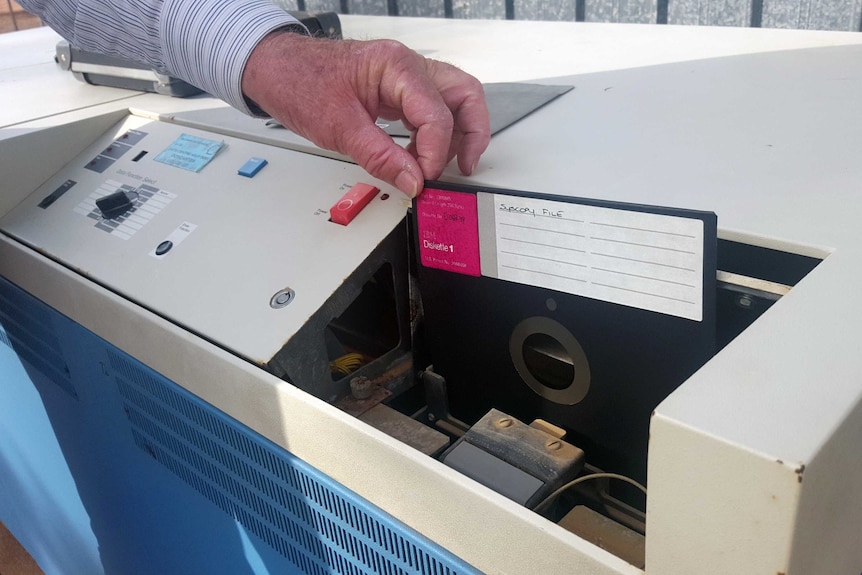 A floppy disk being inserted into an old computer.