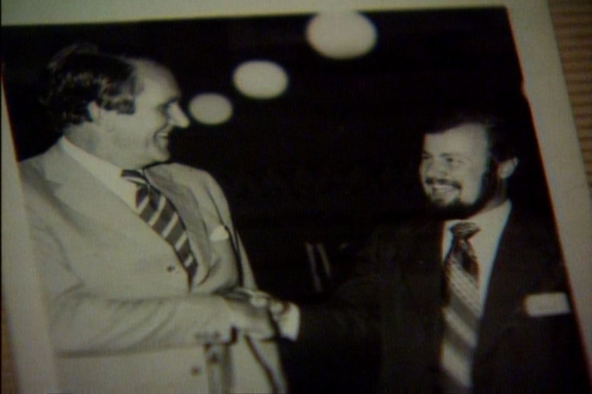 Two men shaking hands and smiling at each other