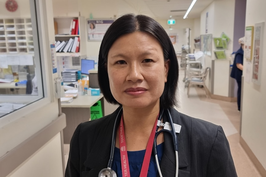 A woman stands in a hospital hallway.