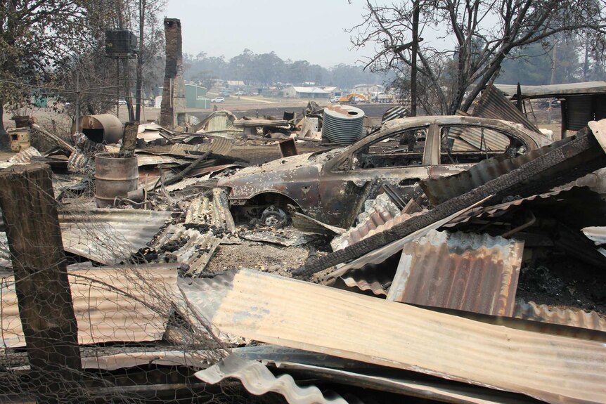 The remains of a burnt out car and house after a bushfire.