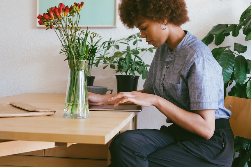 A woman uses a tablet device at her kitchen table