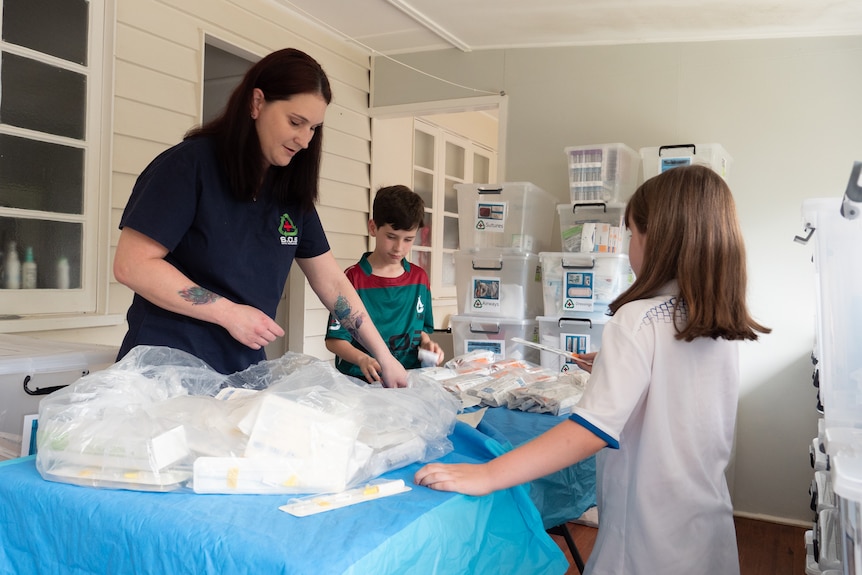 An image of Clair Lane with her two children looking at a table full of medical supplies