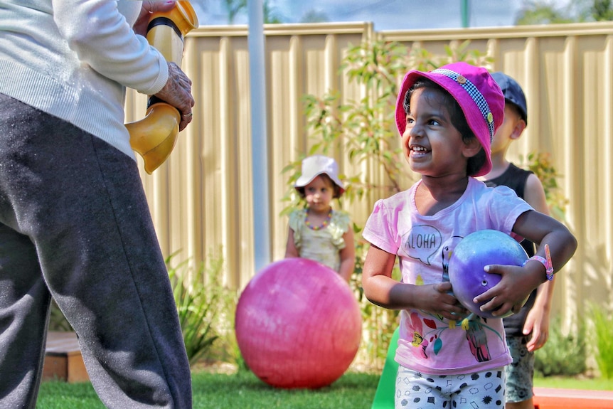 An elderly man with smiling children in a playground