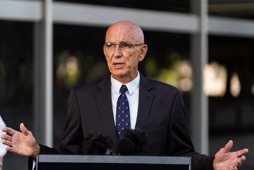 Man in suit speaks behind podium