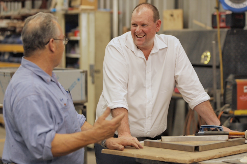 Two men speaking to each other inside a factory. 