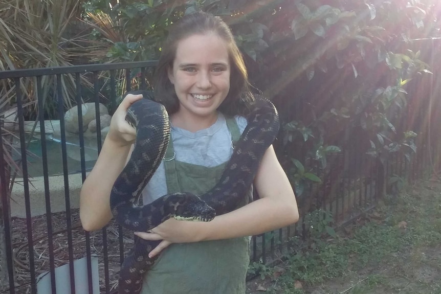 Billie holds a snake and smiles for the camera