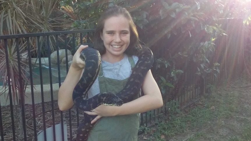 Billie holds a snake and smiles for the camera
