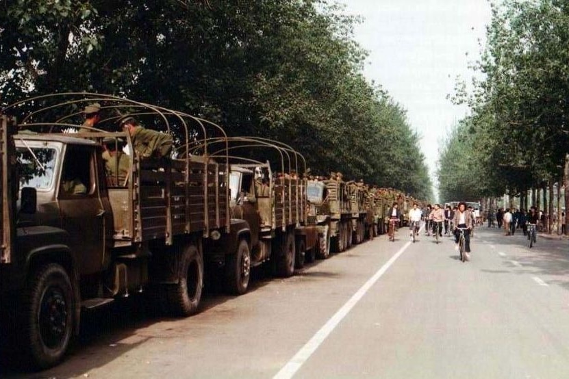 Trucks loaded with soldiers from the Chinese army sit by the side of the road in Beijing