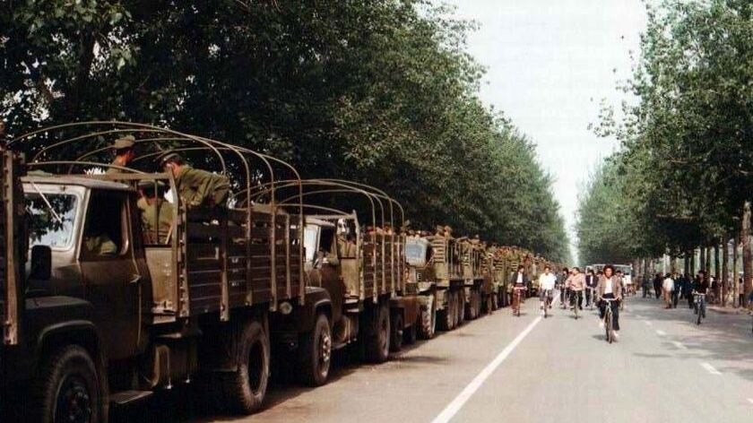 Trucks loaded with soldiers from the Chinese army sit by the side of the road in Beijing