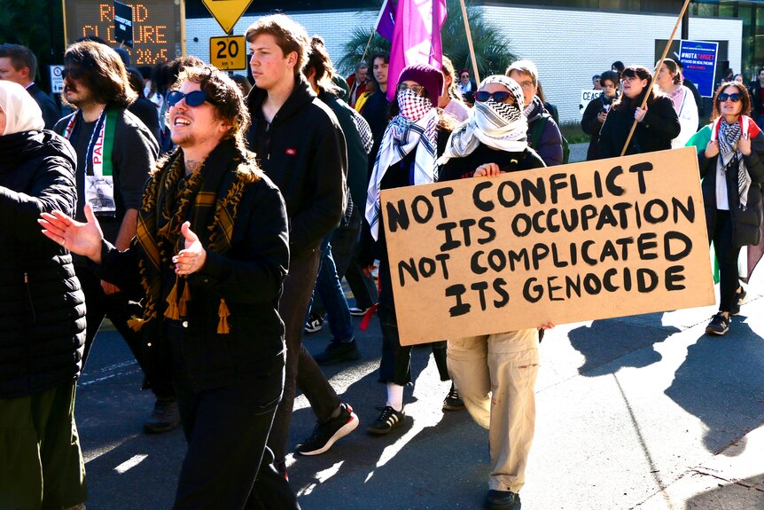 Protesters carrying signs and flags march.