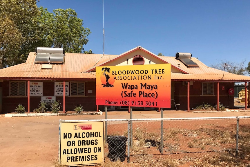 Brown brick house with signs saying Bloodwood Tree Association Wapa Maya (safe place)