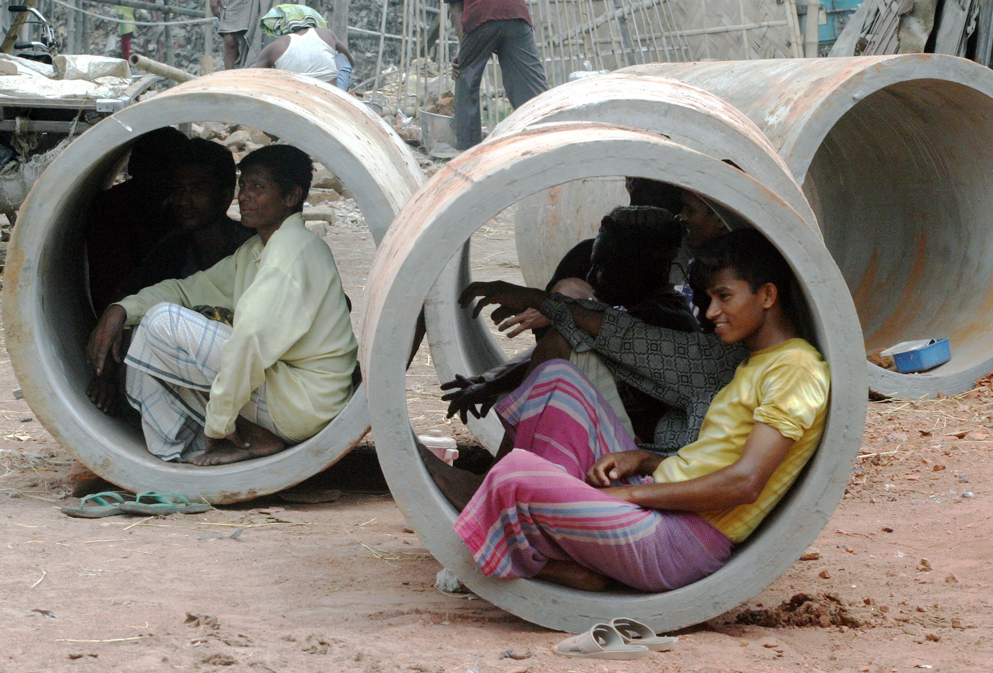 Bangladeshi labourers rest inside pipes