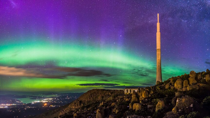 Purple and green aurora over city