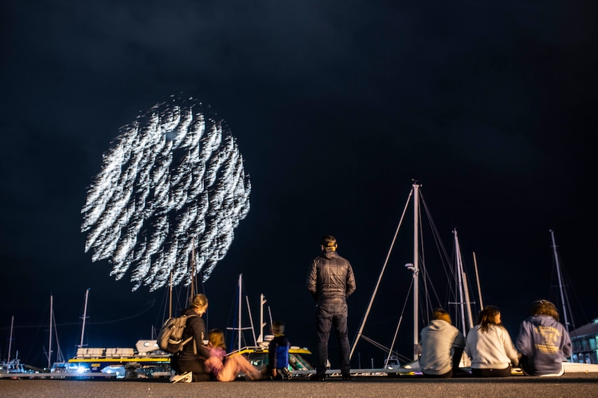 People watching fireworks along the riverside.