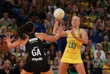 Netballer in the action of throwing the ball with defender with her arms up during a match
