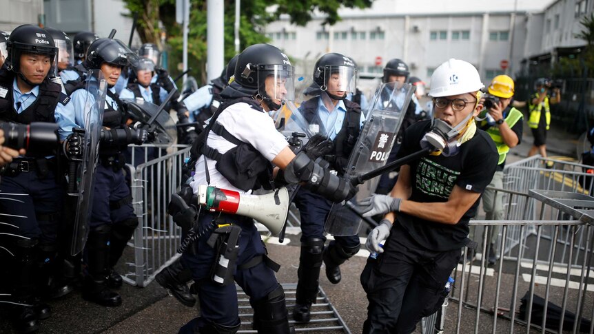 A police officer strikes a protester with a baton on the anniversary of Hong Kong handover to China.