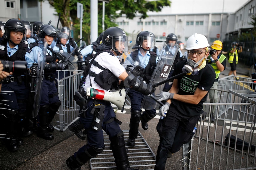 A police officer strikes a protester with a baton on the anniversary of Hong Kong handover to China.