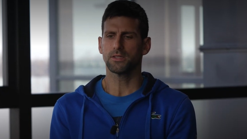 A man in a blue jumper speaks to an interviewer.