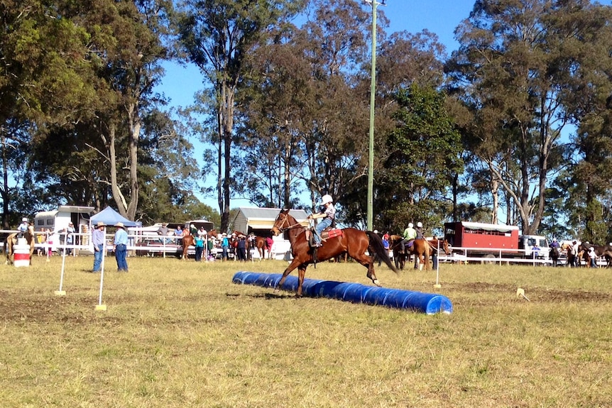 A young boy on a horse jumps over barrels during the bonfield bounce sporting event.