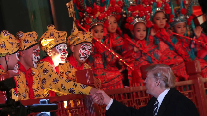 Donald Trump shakes hands with one of many opera performers during his visit to China.