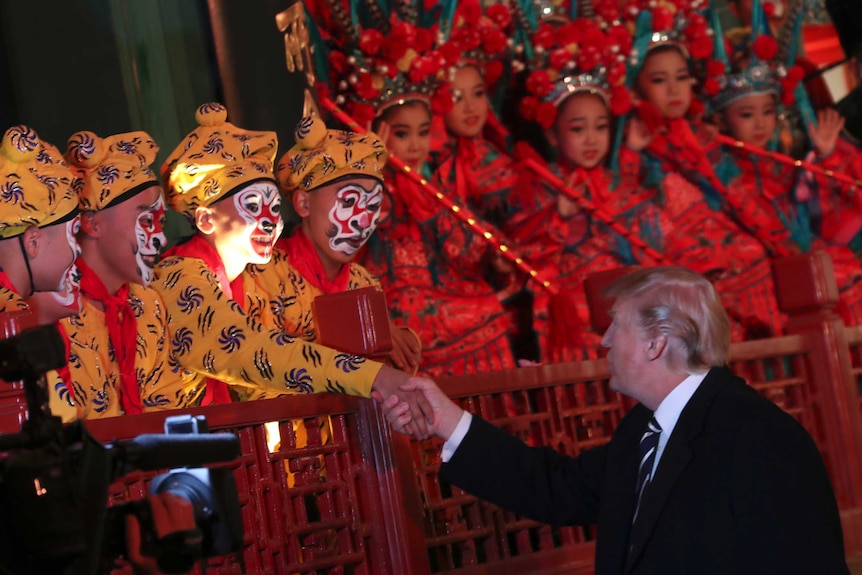 Donald Trump shakes hands with one of many opera performers during his visit to China.