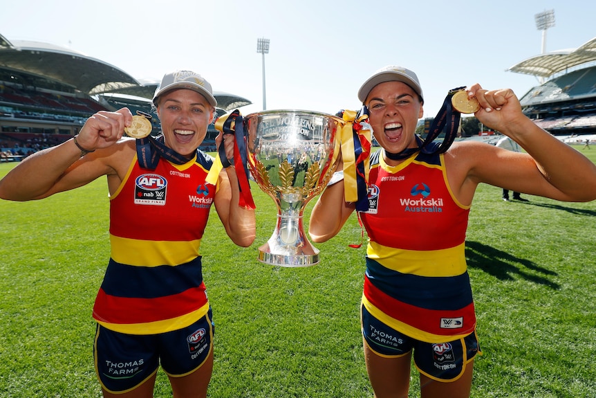 Erin Phillips and Ebony Marinoff pose with the AFLW premiership trophy after winning in 2022