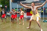 Four Aboriginal boys and one Aboriginal man in tradition cloth and body paint performing a dance.
