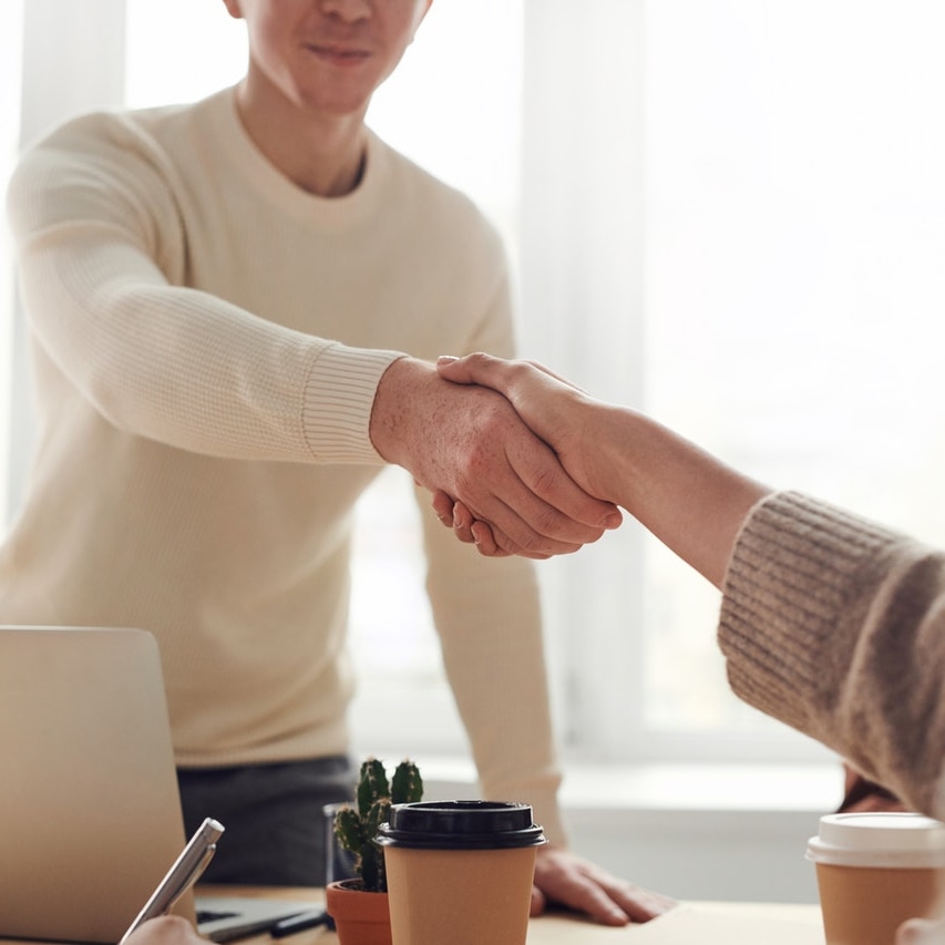 Man and woman near table shake hands.