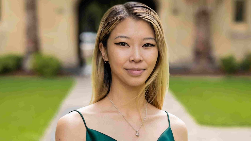 Portrait of Emily Unity wearing a green dress in front of a uni.