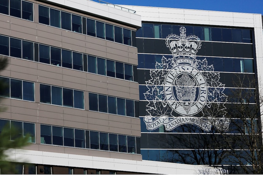A building with a wall of glass windows, with a massive police crest emblazoned on the glass.