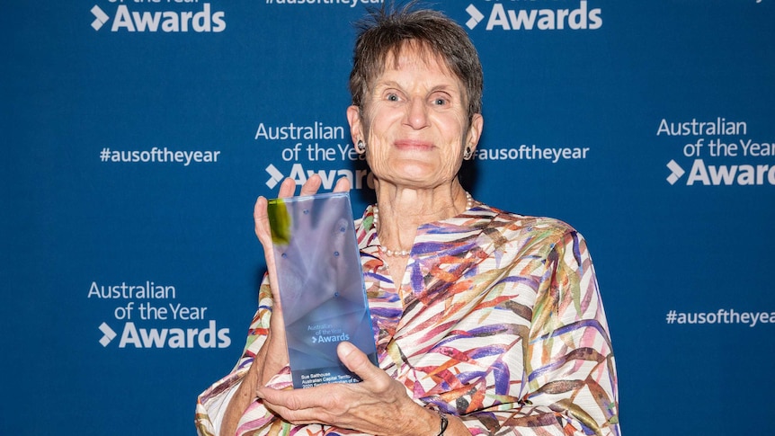 A woman holds an Australian of the Year award