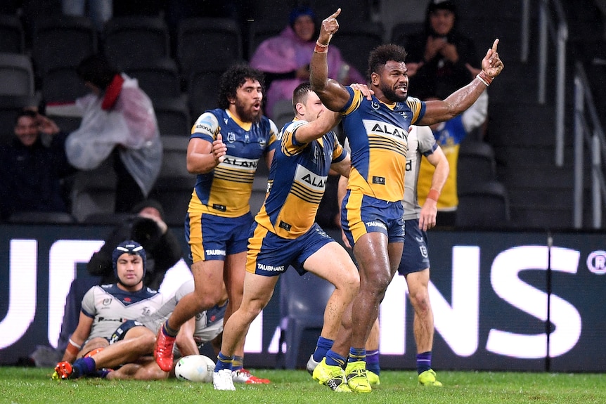 Three Parramatta Eels NRL players celebrate a try against the Melbourne Storm.