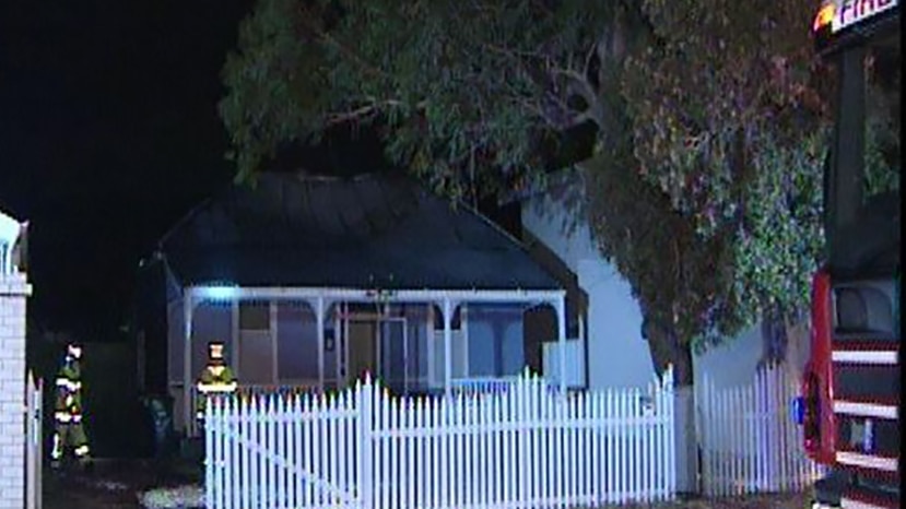 A weatherboard house in Mount Hawthorn at night with firefighters in the front yard.