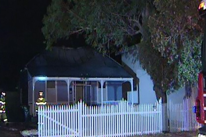 A weatherboard house in Mount Hawthorn at night with firefighters in the front yard.