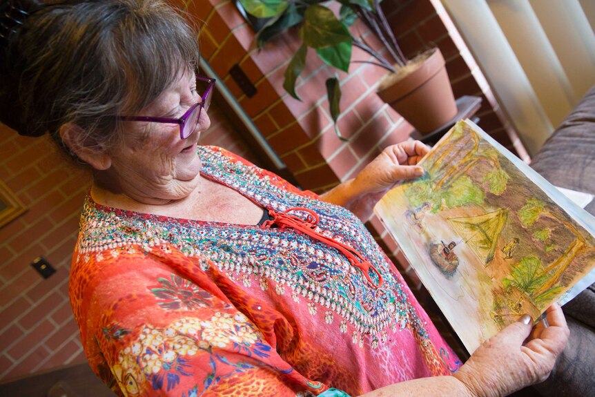 Di holds a painting she drew of a campsite