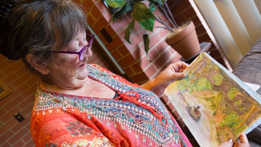 Di holds a painting she drew of a campsite