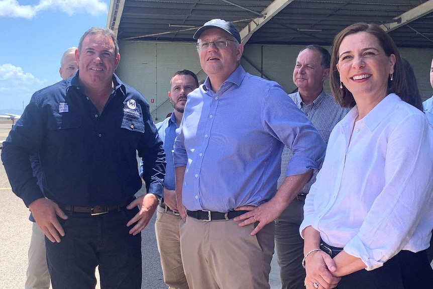 A group of people including Scott Morrison and Deb Frecklington standing under awning on an airport tarmac