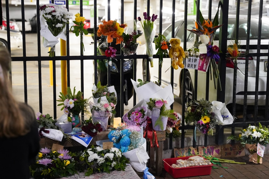 memorial including flowers signs and teddy bears on a car park grilled fence