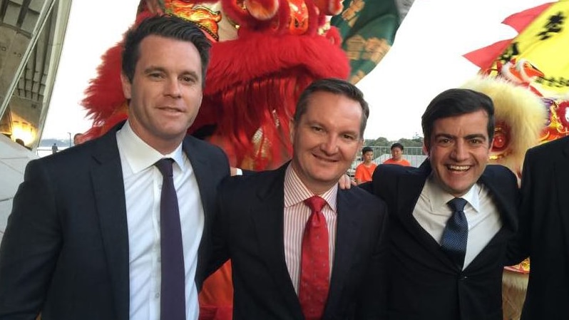 Three men standing with their arms around each other in front of Chinese dragons.