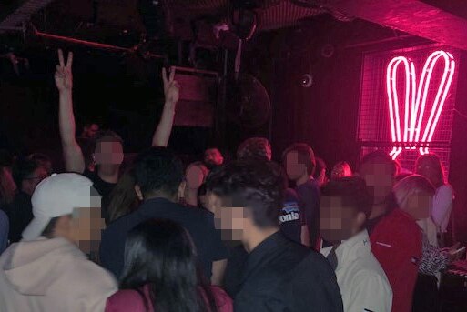 A crowd of people standing on a dancefloor in a nightclub