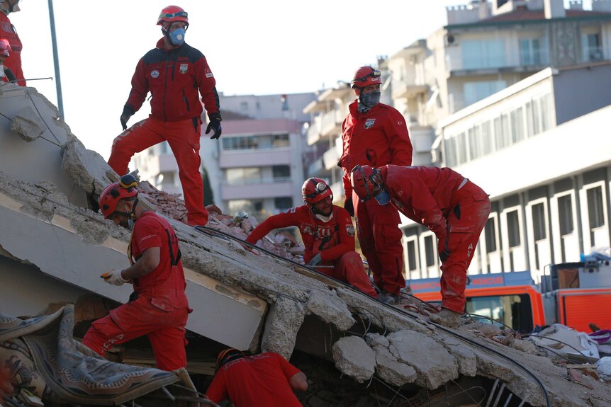 Members of rescue services search in the debris of a collapsed building for survivors.