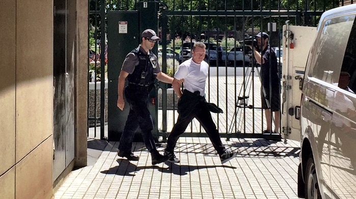 Charles Evans outside court escorted by security.