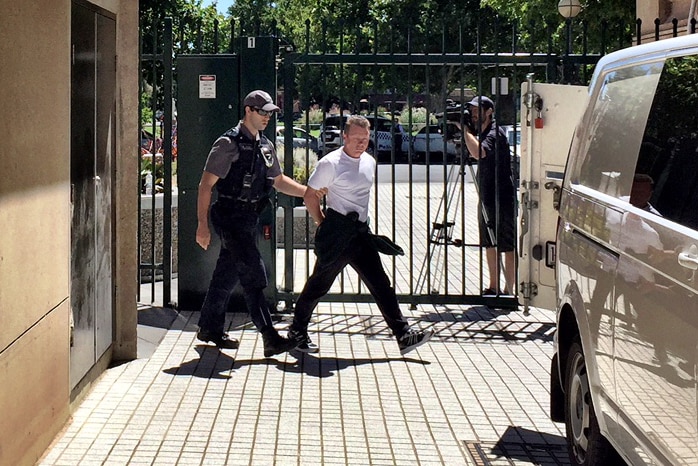 Charles Evans outside court escorted by security.