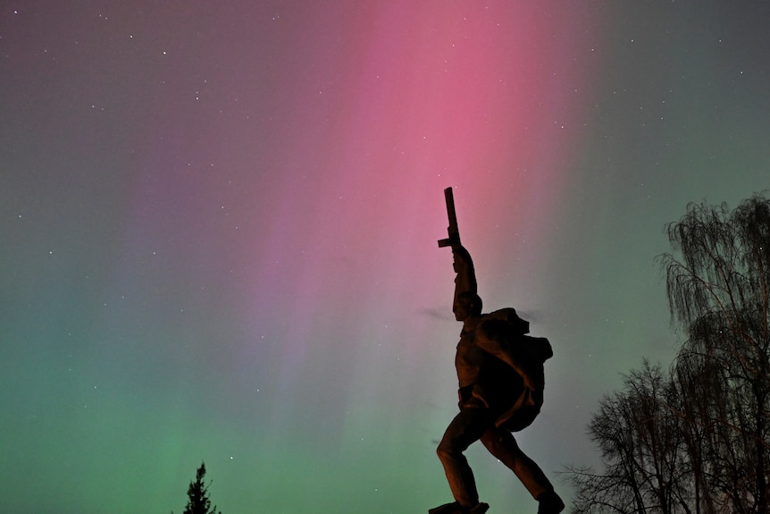A statue illuminated by pink and green lights 